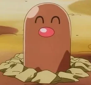 Uma criatura marrom cilíndrica com nariz rosa e olhos fechados, sorrindo, emerge da terra em um cenário rochoso.