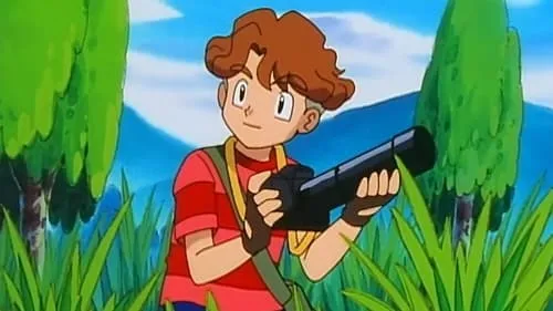 Jovem de anime com cabelo castanho e camisa vermelha segura uma câmera com lente longa. Ele está na floresta entre árvores e grama.