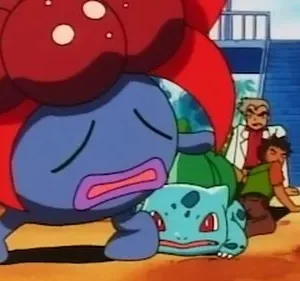 Criatura azul gigante angustiada e outra verde caída no chão. Cinco humanos, incluindo um homem de jaleco, observam preocupados.