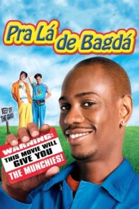 Um homem negro sorridente em primeiro plano segura um cartão vermelho. Atrás,dois homens em roupas coloridas num gramado sob céu azul. Clima cômico.