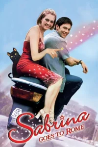 Mulher loira e homem sorridentes em scooter com gato. Ela aponta para estrela mágica. Céu azul e cidade ao fundo. Clima alegre e romântico.
