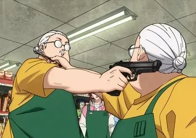 Duas idosas de avental em um mercado. Uma aponta uma pistola para a cabeça da outra. Cena tensa e inesperada.