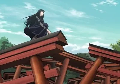 Mulher de cabelo preto e roupa escura agachada sobre vários portões torii vermelhos. Ela observa o horizonte sob um céu azul.