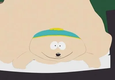 Close-up de personagem de desenho animado gordo com boné azul e sorriso. Seu corpo exagerado e bege preenche a tela.