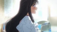 Jovem anime de cabelos escuros e longos, sorrindo e corando, com olhar de surpresa. Fundo interior claro e desfocado, com forte luz.