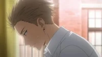 Jovem de anime com cabelo espetado e brinco, cabeça baixa e rosto levemente corado. Fundo desfocado com luz suave.