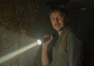 Homem barbudo, tenso, ilumina parede com crescimentos orgânicos em ambiente escuro, número 944.