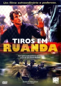 Homem com as mãos ao alto,amedrontado,atrás de uma cerca,sob a mira de uma arma. Abaixo,homens correm em desespero. Cena de conflito intenso.