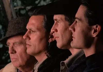 Quatro homens em perfil olham fixamente para a direita. Um idoso de chapéu e três mais jovens, com expressões sérias e clima sombrio.