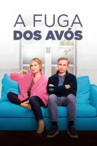 Um casal de idosos sentados em um sofá azul. A mulher sorri em rosa,o homem de braços cruzados parece sério. Fundo claro.
