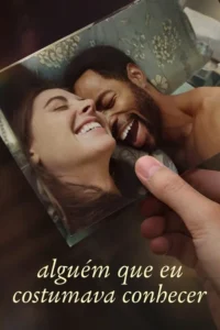 Mão segura foto de casal rindo,ele negro e ela branca,deitados. Expressões de felicidade e carinho em um registro afetivo.