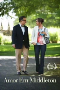 Homem de blazer e mulher sorriem,caminhando por um parque ensolarado. Torres de igreja em fundo verde. Clima romântico e leve.