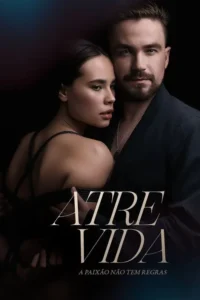 Um casal em close com fundo escuro. Ela,com cordas atadas ao corpo,é abraçada por ele que olha fixamente. Clima sensual e misterioso.