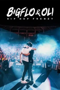 Dois músicos se abraçam no palco,de costas para a plateia. O fundo mostra uma multidão vibrante e luzes azuis e fumaça de show.