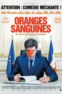Homem de terno azul,com laranja esmagada no rosto,assina documento. Bandeiras francesa e da UE ao fundo.
