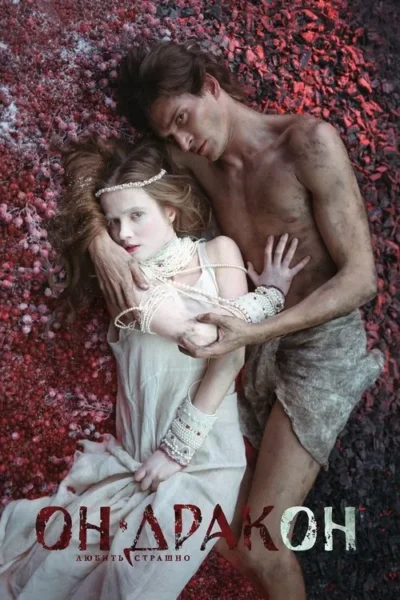 Casal deitado em bagas vermelhas e terra escura. Mulher pálida com pérolas e homem rude abraçam-se, num clima intenso e misterioso.