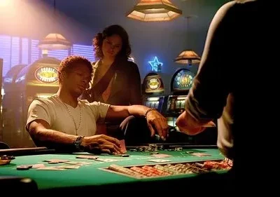 Homem joga cartas numa mesa de pôquer verde em cassino, com mulher observando. Máquinas caça-níqueis ao fundo. Clima tenso.