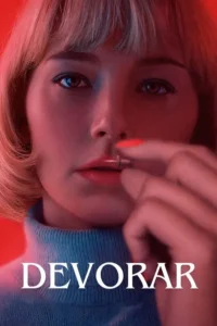 Close-up de mulher loira com franja em fundo vermelho. Ela segura um objeto prateado entre os lábios,com unha laranja vibrante.