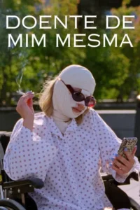Mulher com rosto enfaixado e óculos escuros,em cadeira de rodas,fumando e olhando o celular. Fundo verde borrado.