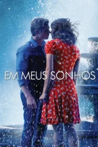 Um homem e uma mulher se inclinam para se beijar sob respingos de água. Ela de vestido florido vermelho, ele de camisa azul. Cenário romântico.