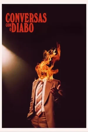 Pôster: um homem de terno marrom e gravata, com a cabeça envolta em chamas vívidas, em um palco escuro sob um foco de luz.