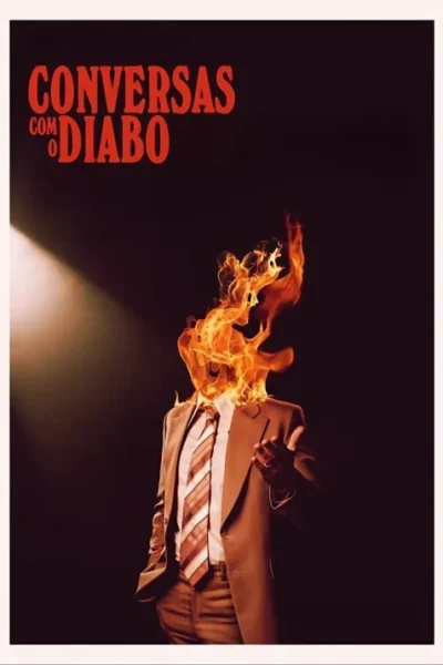 Pôster: um homem de terno marrom e gravata, com a cabeça envolta em chamas vívidas, em um palco escuro sob um foco de luz.