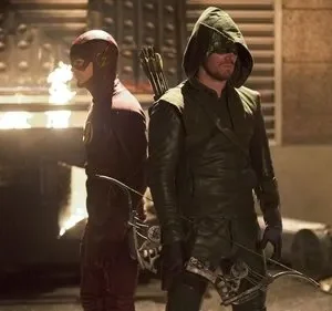 Dois heróis mascarados, um de vermelho com raio e outro de verde com arco, de costas numa rua escura e urbana.