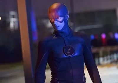 Figura mascarada de traje escuro com raio no peito e olhos brilhantes. Noite urbana, luzes de emergência. Clima sombrio.