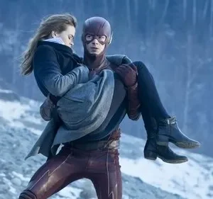 Herói mascarado de vermelho resgata mulher pálida em seus braços, em paisagem gelada e nevada. Clima de perigo e urgência.