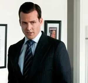 Homem de terno pinstripe e gravata, com olhar direto e confiante, em um escritório moderno com quadros na parede.