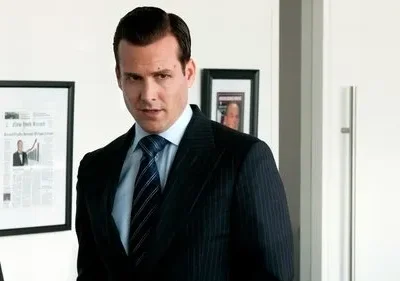 Homem de terno pinstripe e gravata, com olhar direto e confiante, em um escritório moderno com quadros na parede.