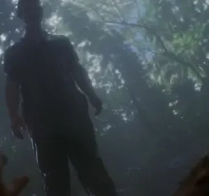 Homem sombrio de pé sobre figura olhando para cima, em floresta densa e neblinosa. Luz filtrada, clima tenso.