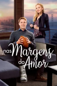 Homem com bota ortopédica e bola de futebol sentado,mulher com prancheta sorrindo atrás. Vista de cidade e ponte ao pôr do sol.