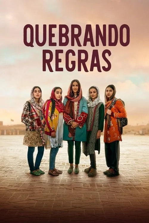 Cinco mulheres jovens com roupas coloridas e véus, posam com expressões sérias num cenário urbano aberto sob um céu claro e suave.