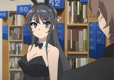 Em uma biblioteca, uma garota de cabelo escuro em roupa de coelha e um laço, olha para um garoto de costas que a observa.