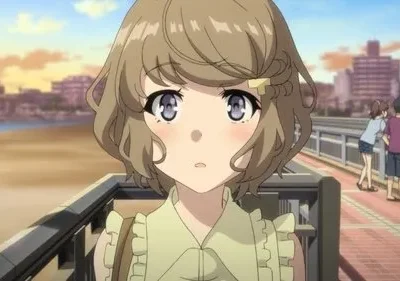 Jovem anime com cabelo castanho e olhos grandes olhando para frente, bochechas coradas, em um calçadão à beira-mar ao pôr do sol.