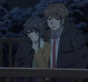 Um casal de anime em casacos grossos está em uma varanda nevada à noite. O garoto olha para frente, a garota para baixo, com árvores escuras ao fundo.