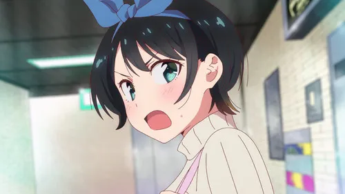 Rent-a-Girlfriend – T01E07:Namorada Temporária e Namorada 1 Anime girl com cabelo curto preto,laço azul e olhos teal arregalados. Bochechas coradas,boca aberta em surpresa,em um corredor claro.