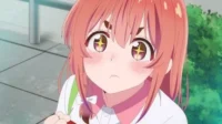 Jovem anime de cabelo rosa com olhos arregalados e brilhantes, bochechas coradas e expressão tímida, em cenário externo.