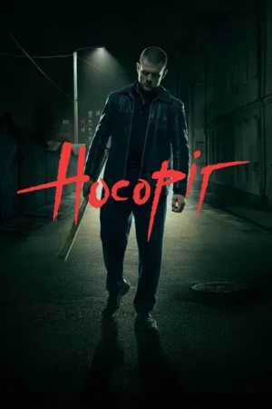 Homem sério de jaqueta escura caminha em beco sombrio à noite, com um taco no ombro. Um poste de luz ilumina a cena tensa.