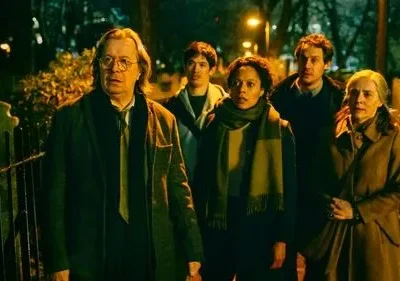 Um grupo de seis pessoas em um cemitério noturno. Todos parecem tensos sob a iluminação verde-escura do ambiente misterioso.