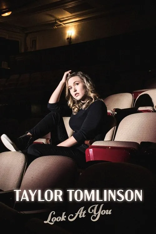 Taylor Tomlinson:Look at You 1 Mulher loira em roupa escura sentada em poltronas de cinema esvaziado,pés na cadeira. Olhar direto e clima intimista.