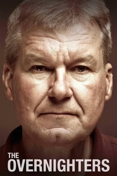 Rosto de um homem com cabelos grisalhos e expressão séria e intensa, em close-up contra fundo escuro. Clima dramático.