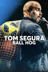 Tom Segura: Ball Hog 8 Homem barbudo careca com microfone e uma rede de bolas esportivas no ombro, em palco escuro.