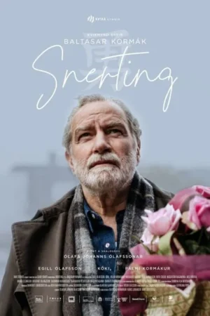 Homem barbudo de casaco olha para cima, pensativo, com buquê de rosas cor-de-rosa no canto. Cenário azul-cinzento suave.