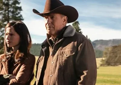 Homem de chapéu de cowboy e mulher séria em paisagem campestre. Céu azul, montanhas e florestas ao fundo. Clima dramático.