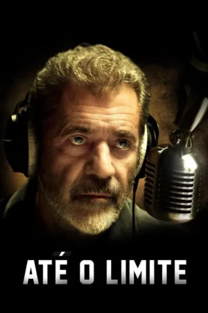 Um homem barbudo de meia-idade com fones de ouvido e olhar sério, ao lado de um microfone vintage em fundo escuro.