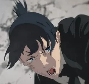 Jovem de cabelo preto e rabo de cavalo, ferido e sangrando no rosto, grita e rasteja com fúria em cenário de destruição.