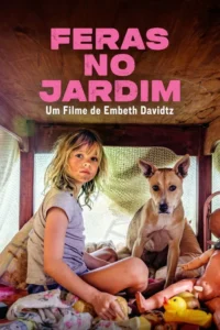 Uma menina com o rosto sujo e um cachorro marrom olham para frente, sentados dentro de um abrigo de madeira com brinquedos.