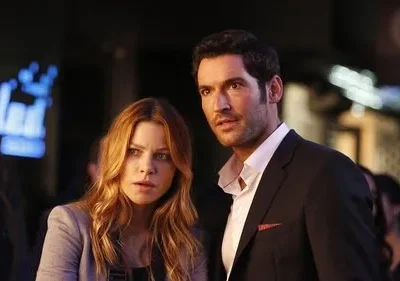Um homem de terno e uma mulher com expressões tensas/surpresas, em uma cena noturna urbana com luzes desfocadas ao fundo.
